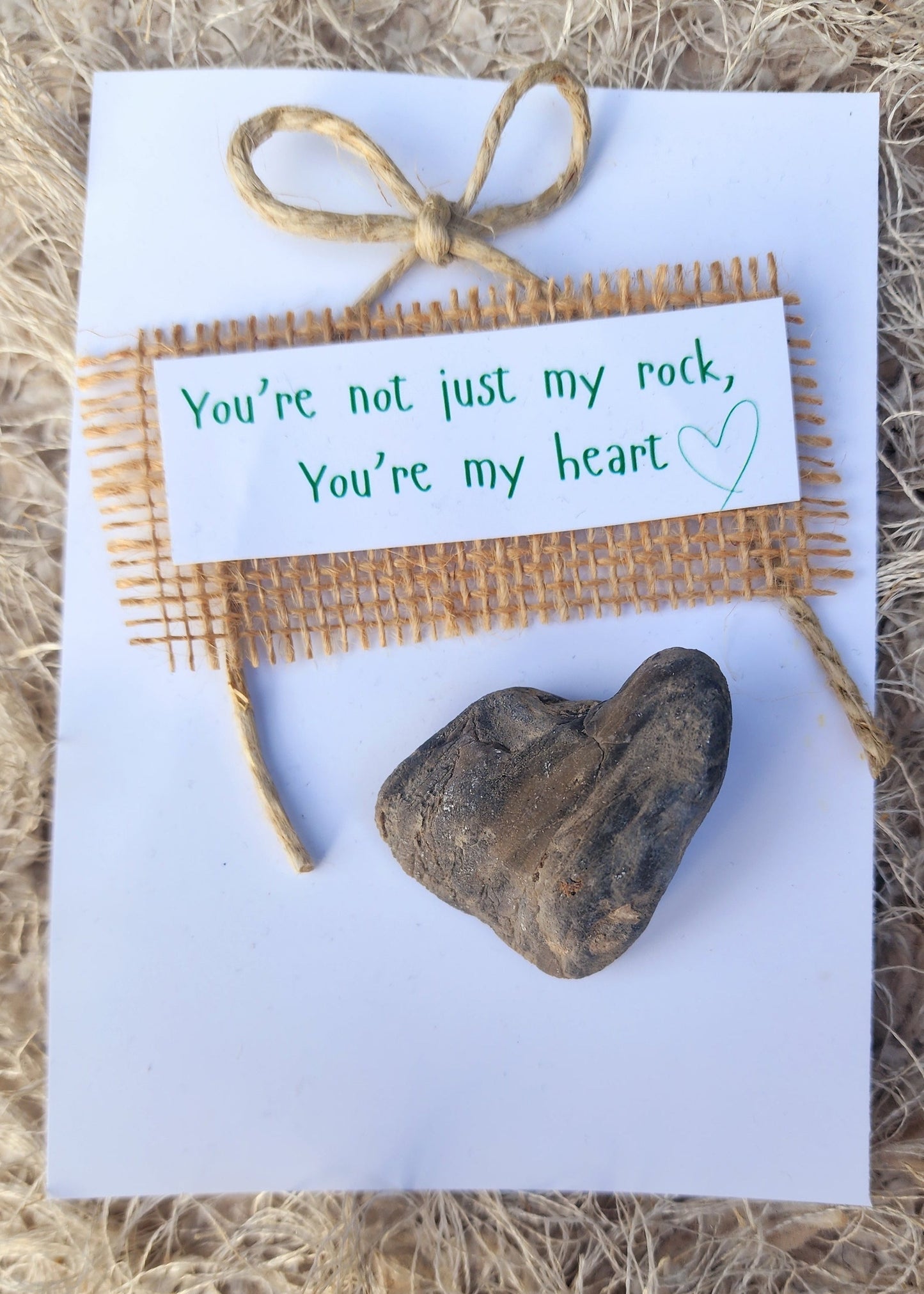 Card with a rock and burlap ribbon on a textured surface