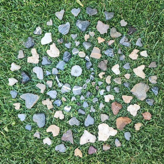 Circular arrangement of small heart shaped rocks on grass
